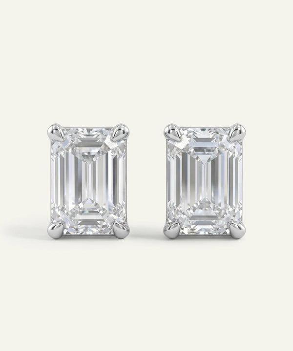 Pair of emerald-cut diamond stud earrings on a white background