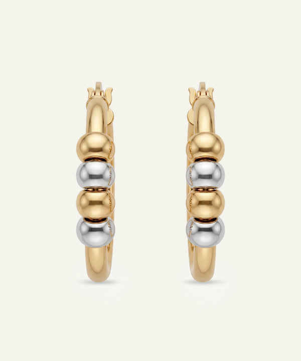 Gold and silver hoop earrings on a light beige background