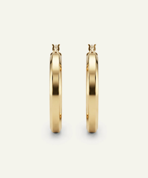 Gold hoop earrings on a light beige background