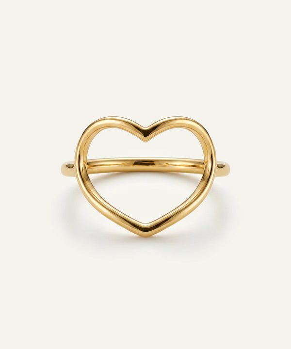 Gold heart-shaped ring on a light beige background
