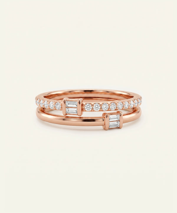A pair of rose gold stacking rings with baguette and round-cut clear stones, displayed on a clean off-white background.