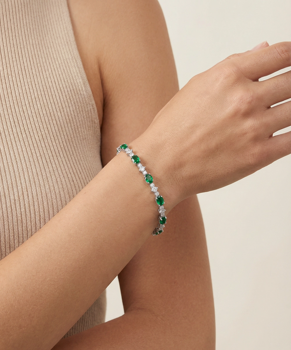 Bracelet with green and white stones on a wrist against a neutral background