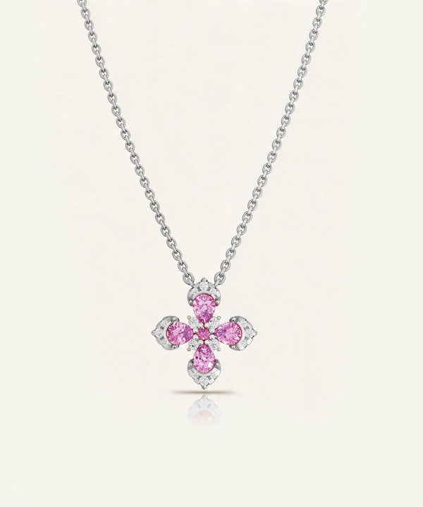 A silver-toned cross pendant necklace featuring four pink gemstones and small clear accent stones, displayed on a clean off-white background.