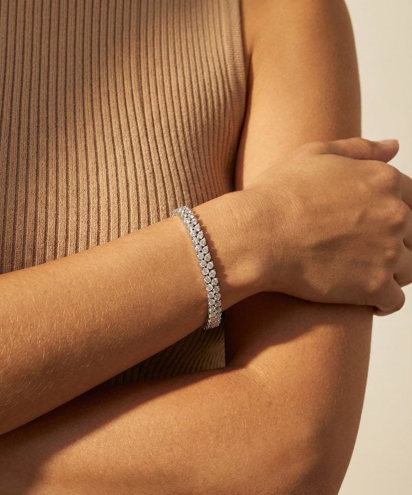 Close-up of a person wearing a silver bracelet on a beige background
