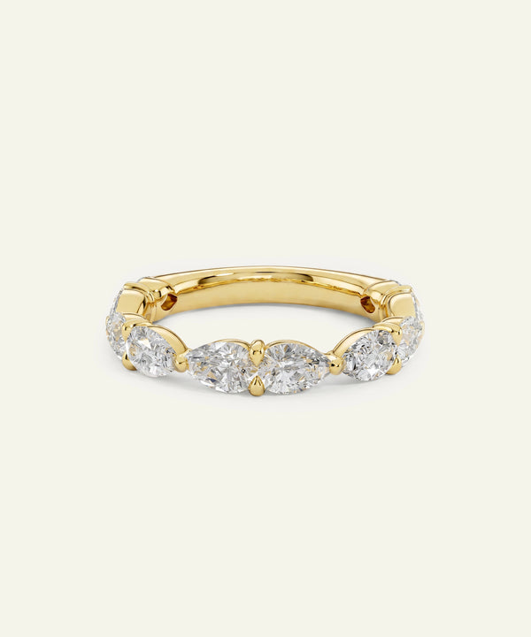 A yellow gold eternity ring featuring marquise-cut and round brilliant-cut diamonds, set against a solid off-white background.