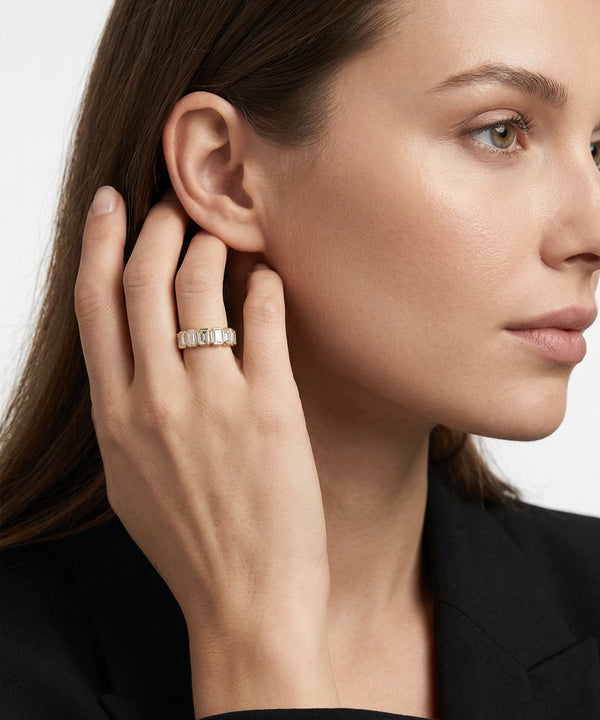 Close-up of a woman wearing a diamond earring with a neutral background