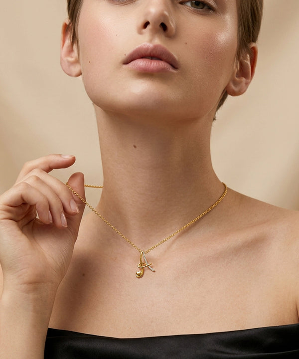 Woman wearing a gold necklace with a pendant against a beige background
