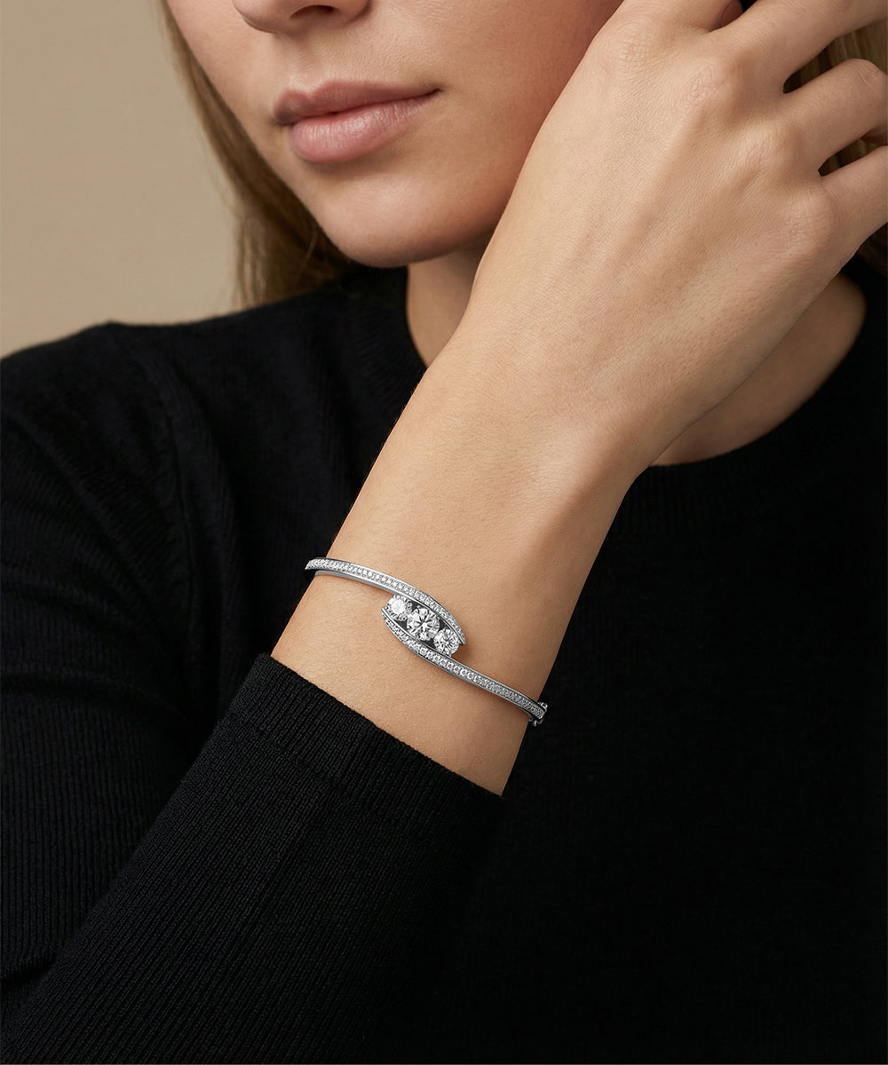 Woman wearing a silver bracelet with a diamond on a beige background