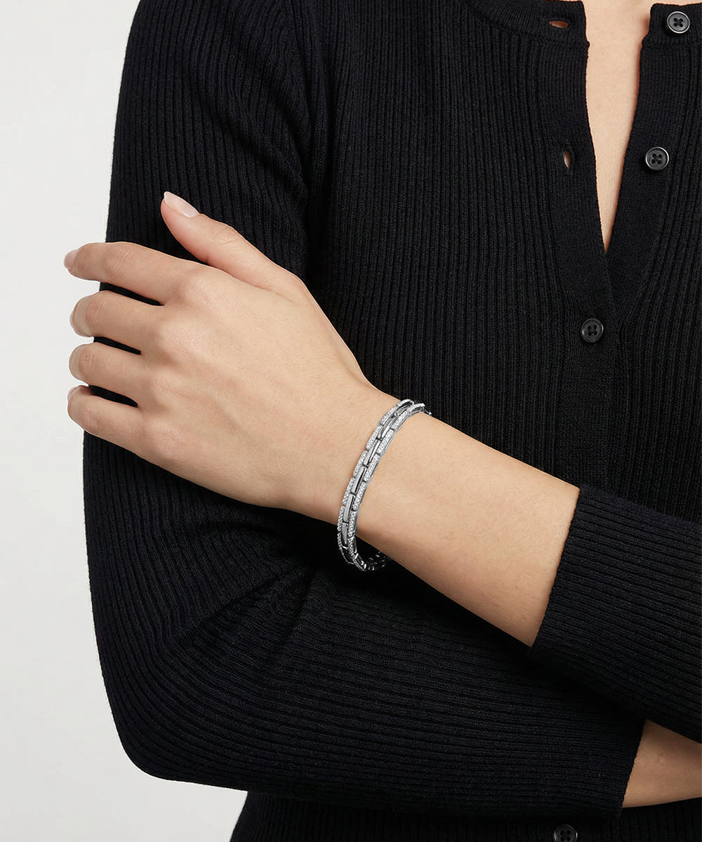 Person wearing a silver bracelet on a plain background