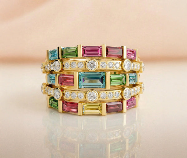 Multicolored gemstone ring with gold band on a reflective surface