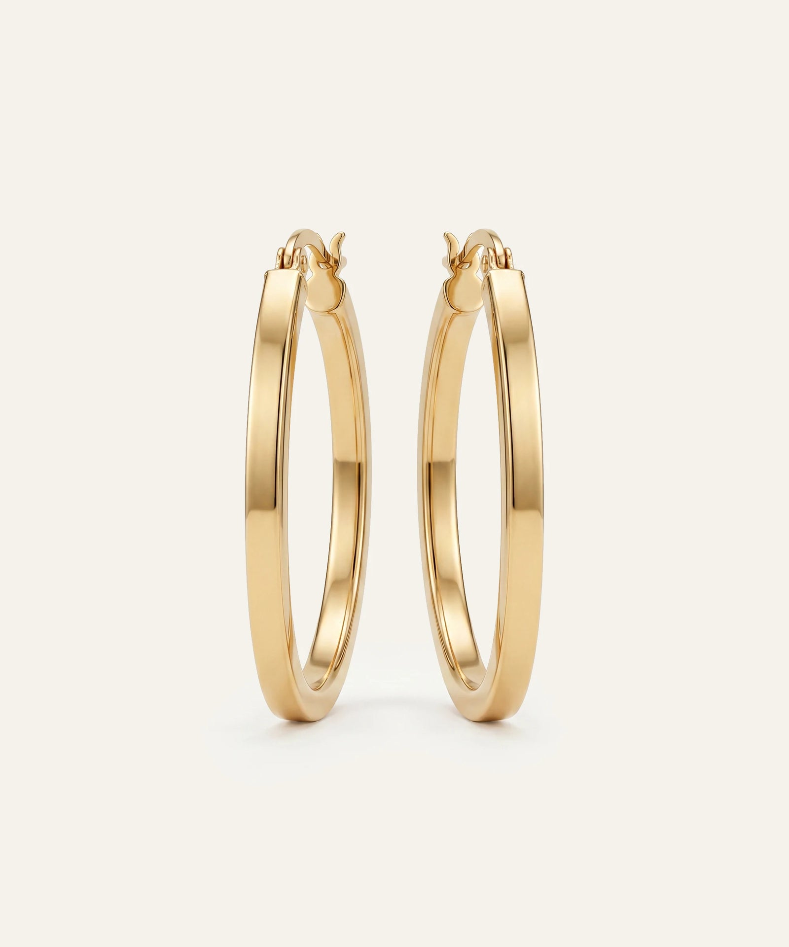 Gold hoop earrings on a light beige background