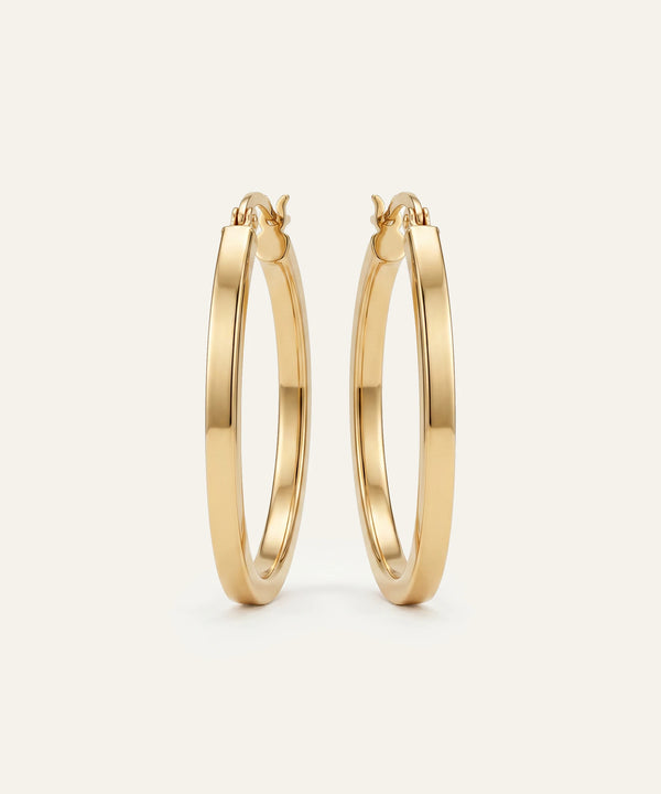 Gold hoop earrings on a light beige background