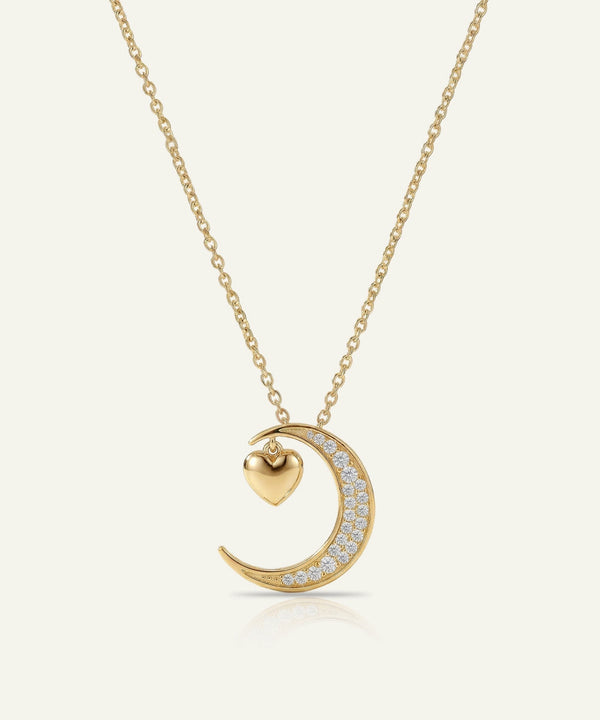 Gold necklace with a crescent moon and heart pendant on a white background