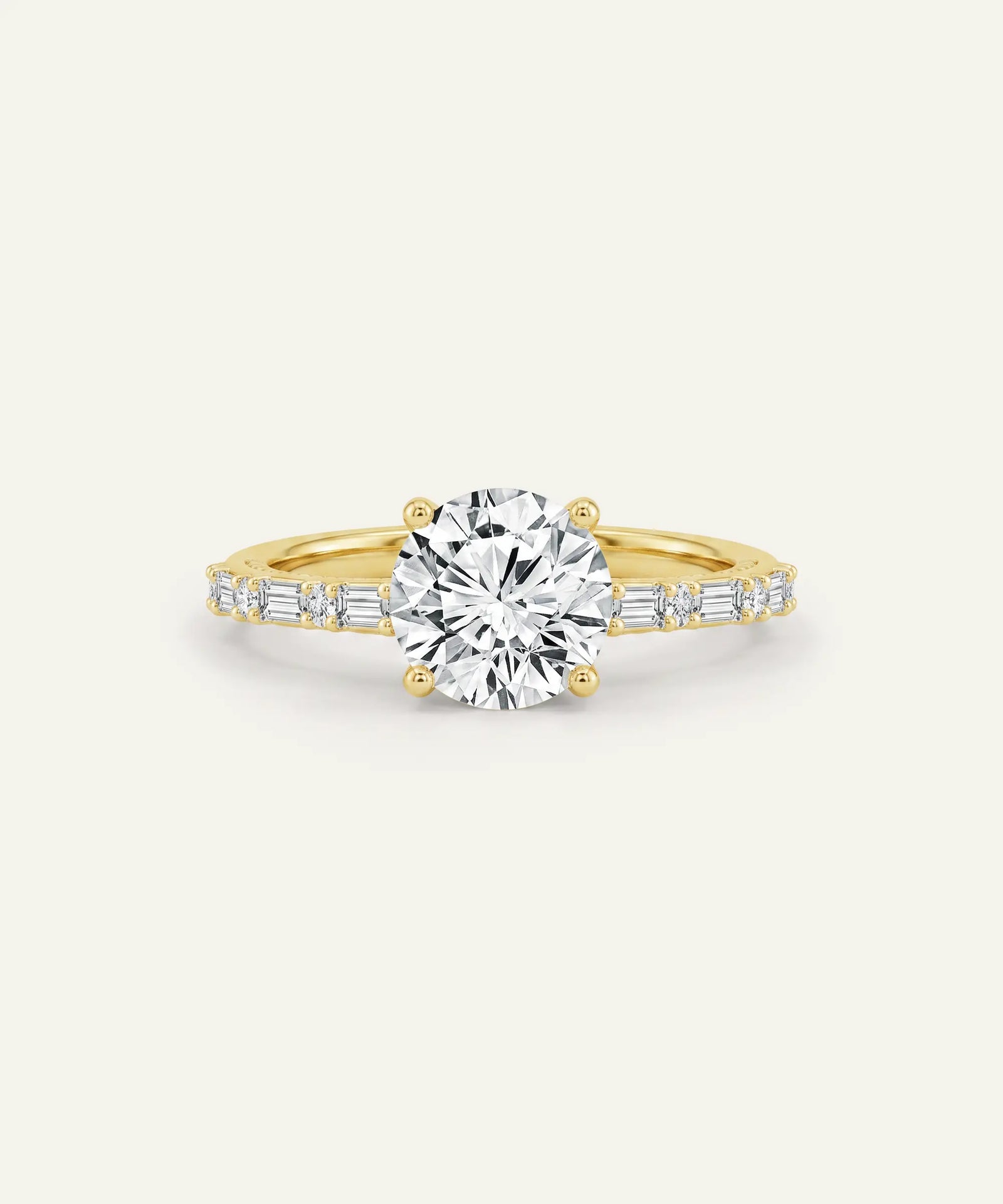 A yellow gold engagement ring featuring a large round-cut center stone and baguette side stones, set against a plain off-white background.