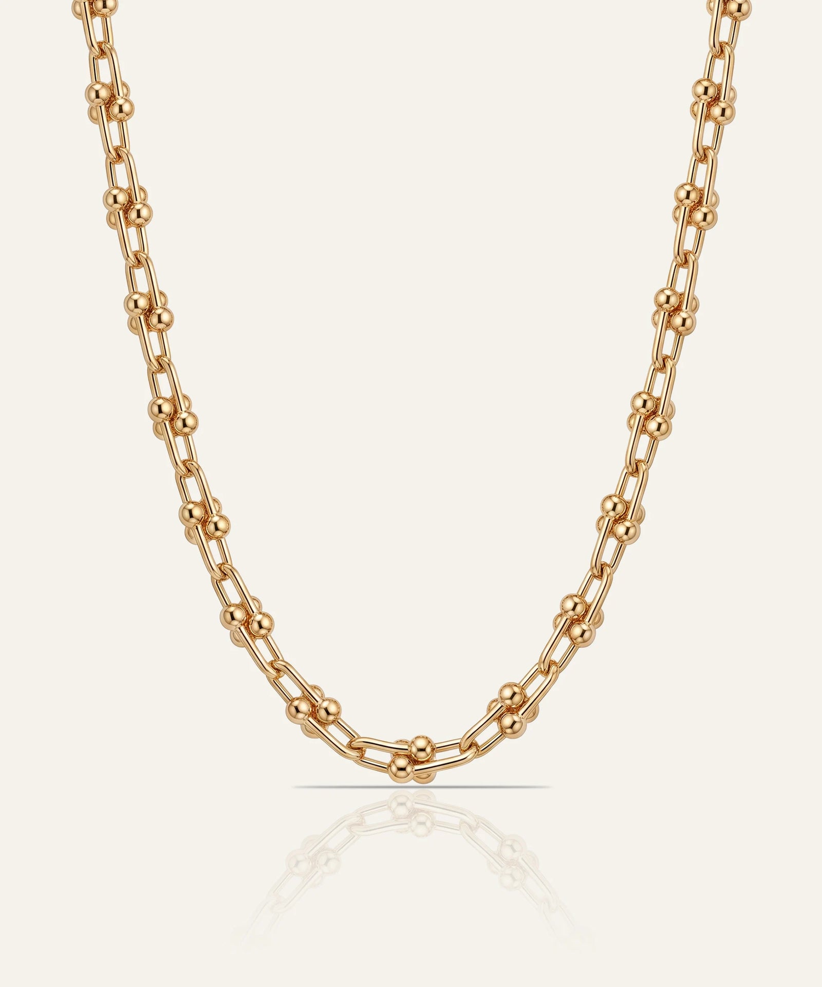 Gold chain necklace on a light beige background