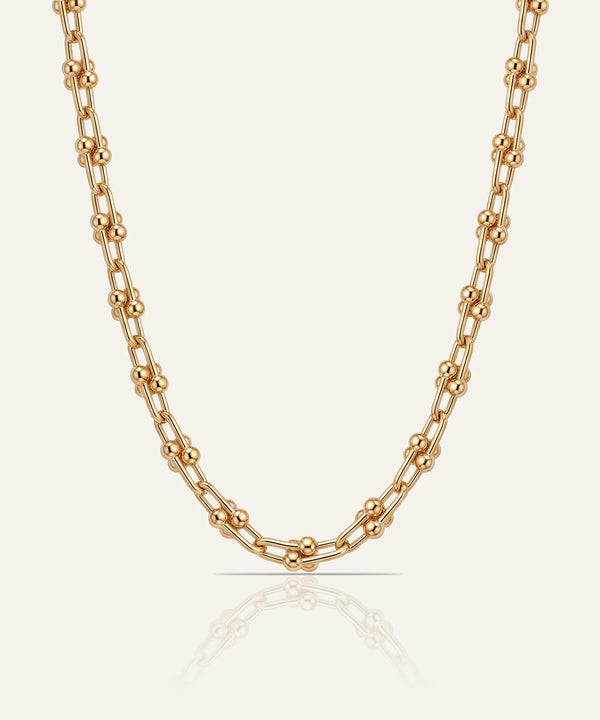 Gold chain necklace on a light beige background