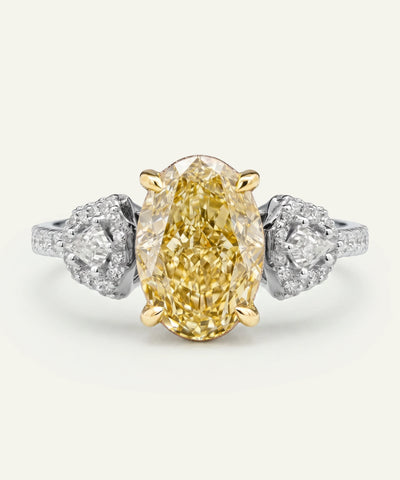 Gold ring with a yellow diamond and silver side stones on a white background