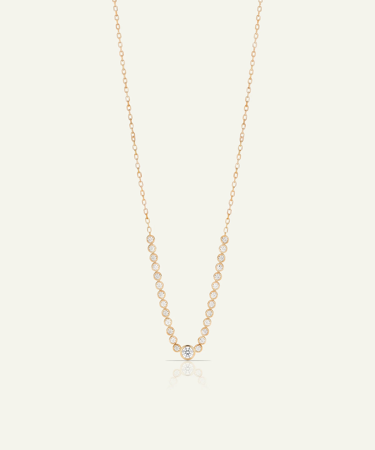 A delicate rose gold chain necklace featuring a V-shaped pendant adorned with small, round clear gemstones, set against a solid off-white background.