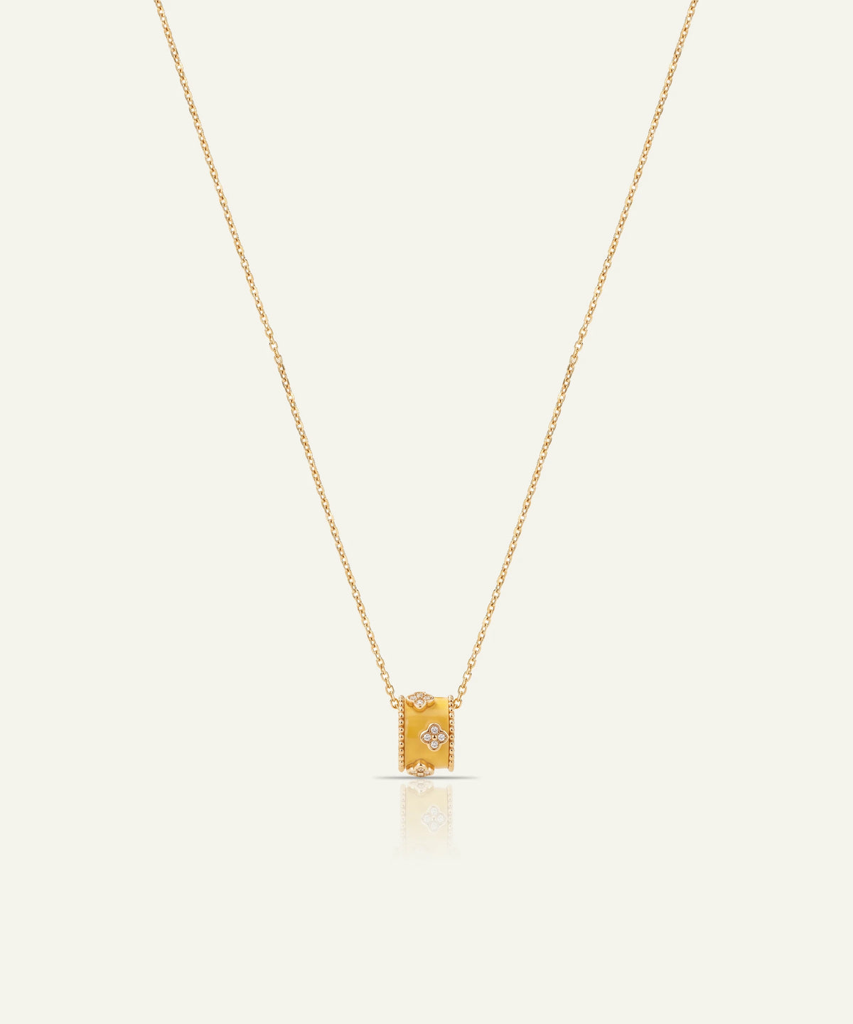 A delicate gold chain necklace with a small rectangular gold pendant featuring a central clear gemstone, displayed against a solid off-white background.
