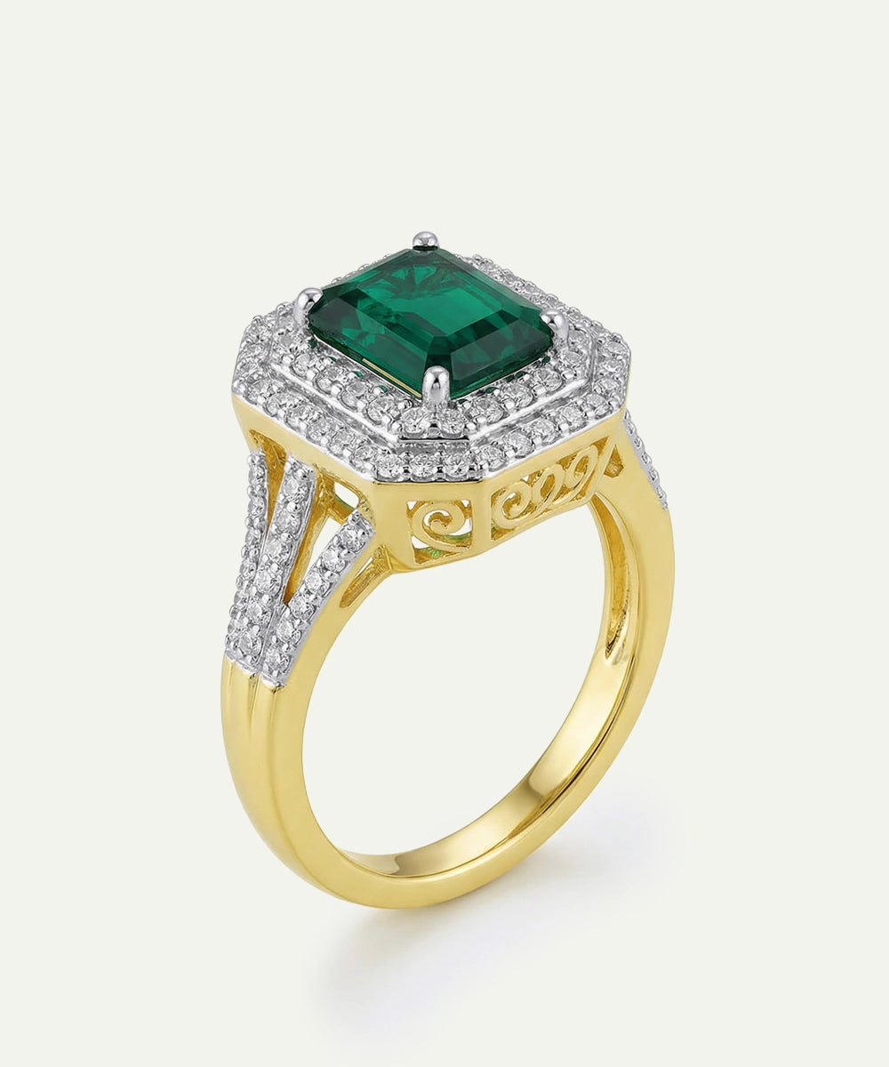Gold ring with a green gemstone and diamond accents on a white background