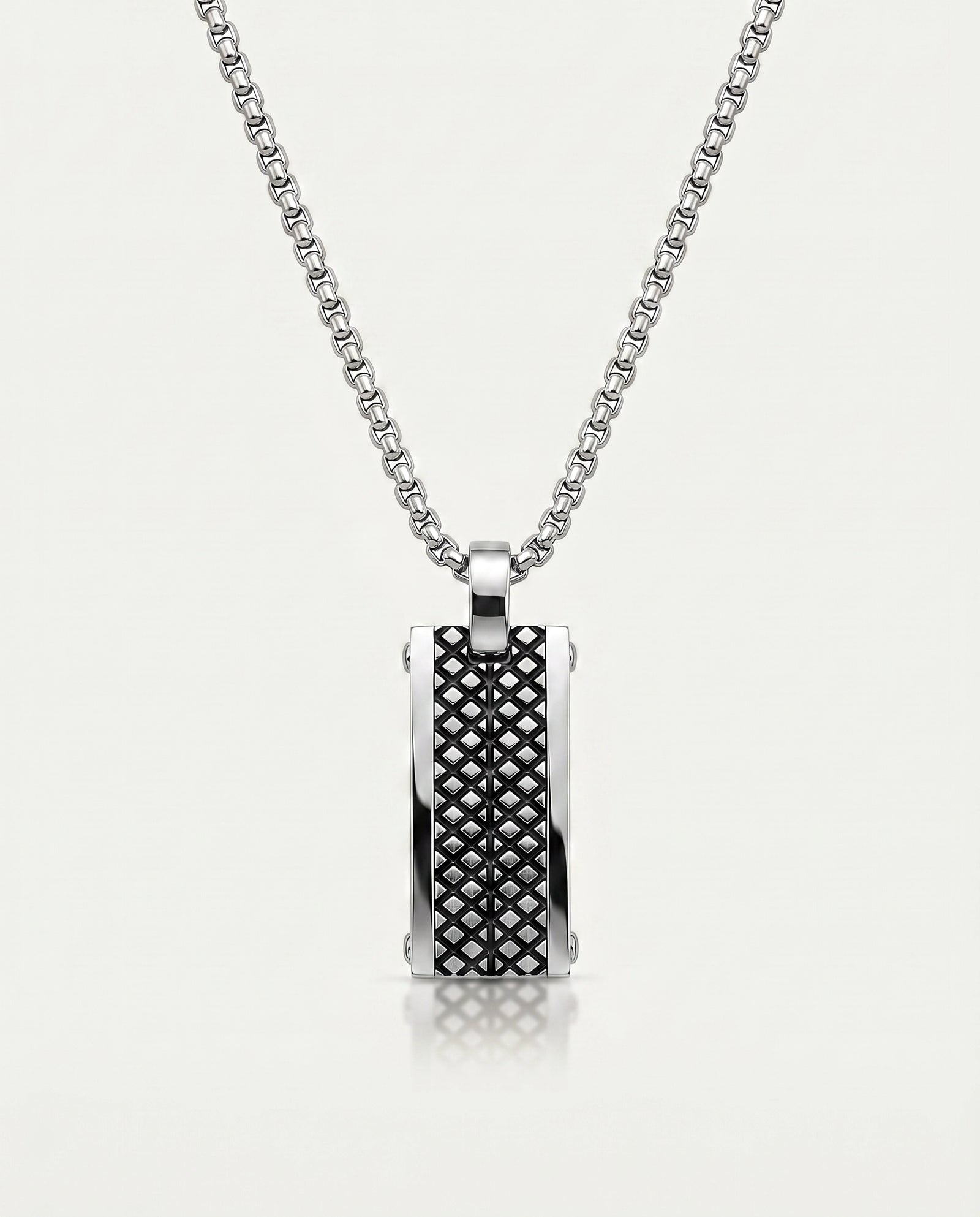 A silver-toned rectangular pendant necklace with a textured black diamond-pattern center panel, suspended from a matching box chain against a light gray background.