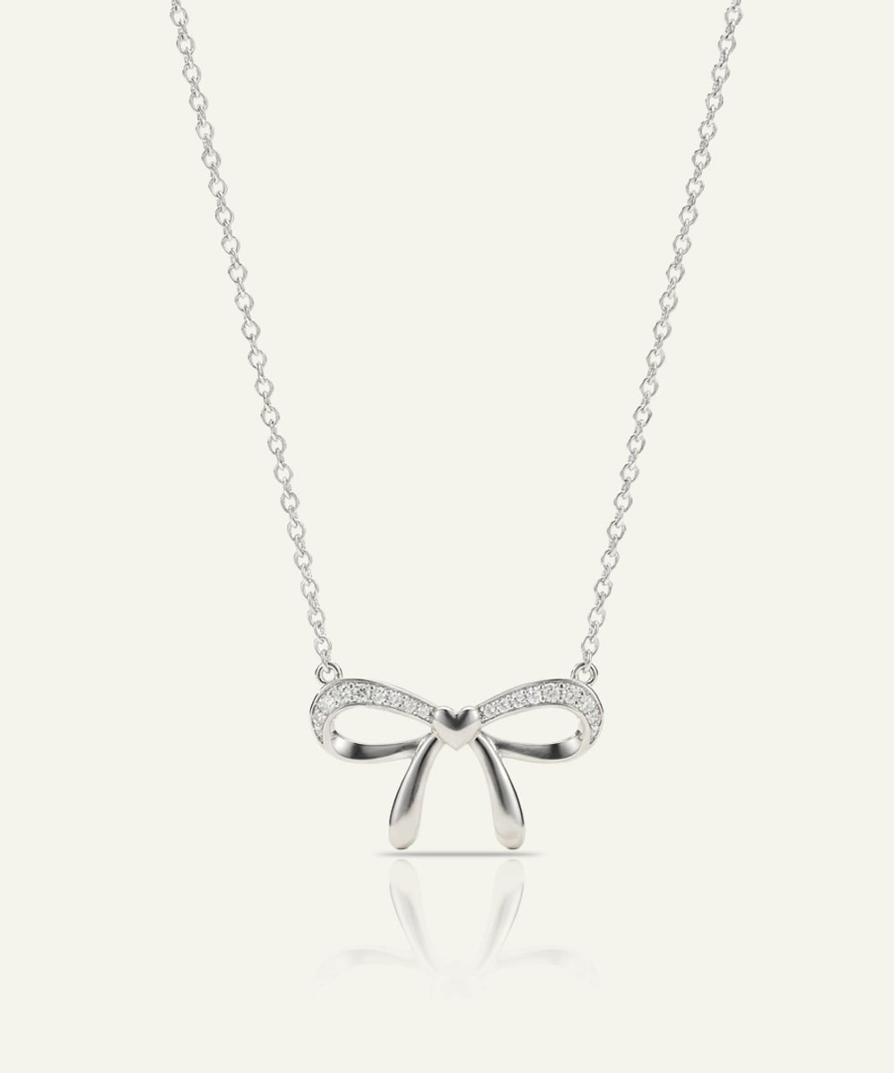 Silver bow-shaped pendant necklace on a white background