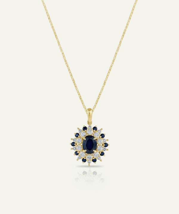 Gold necklace with a pendant featuring a blue gemstone on a white background