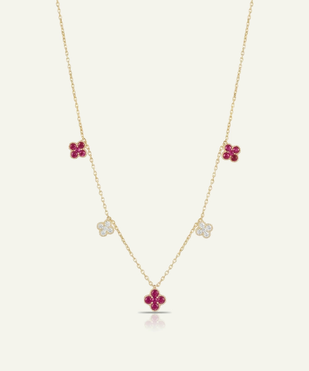 Gold necklace with red flower-shaped pendants on a white background