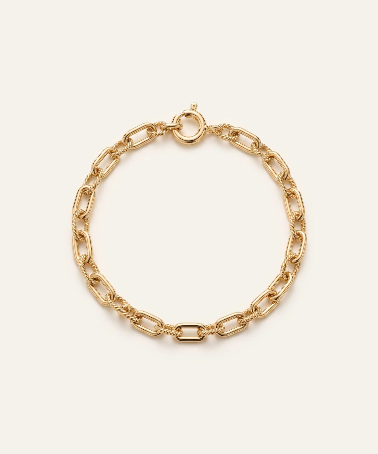 Gold chain bracelet on a light beige background