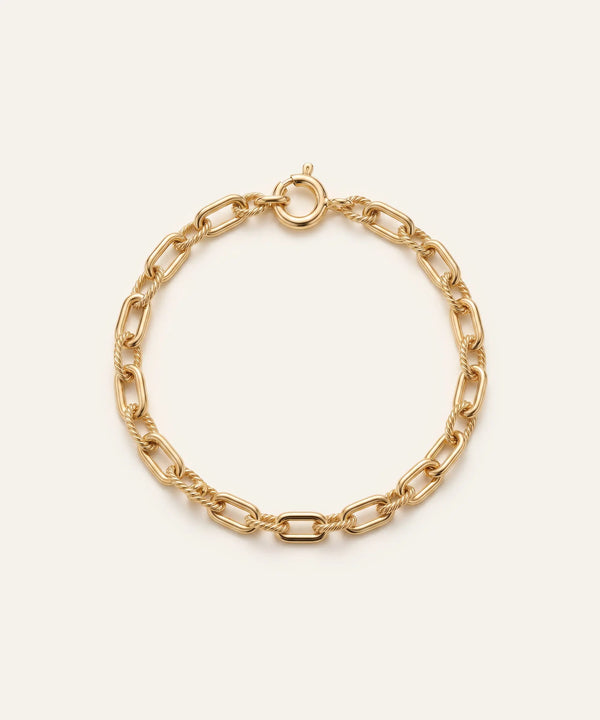 Gold chain bracelet on a light beige background