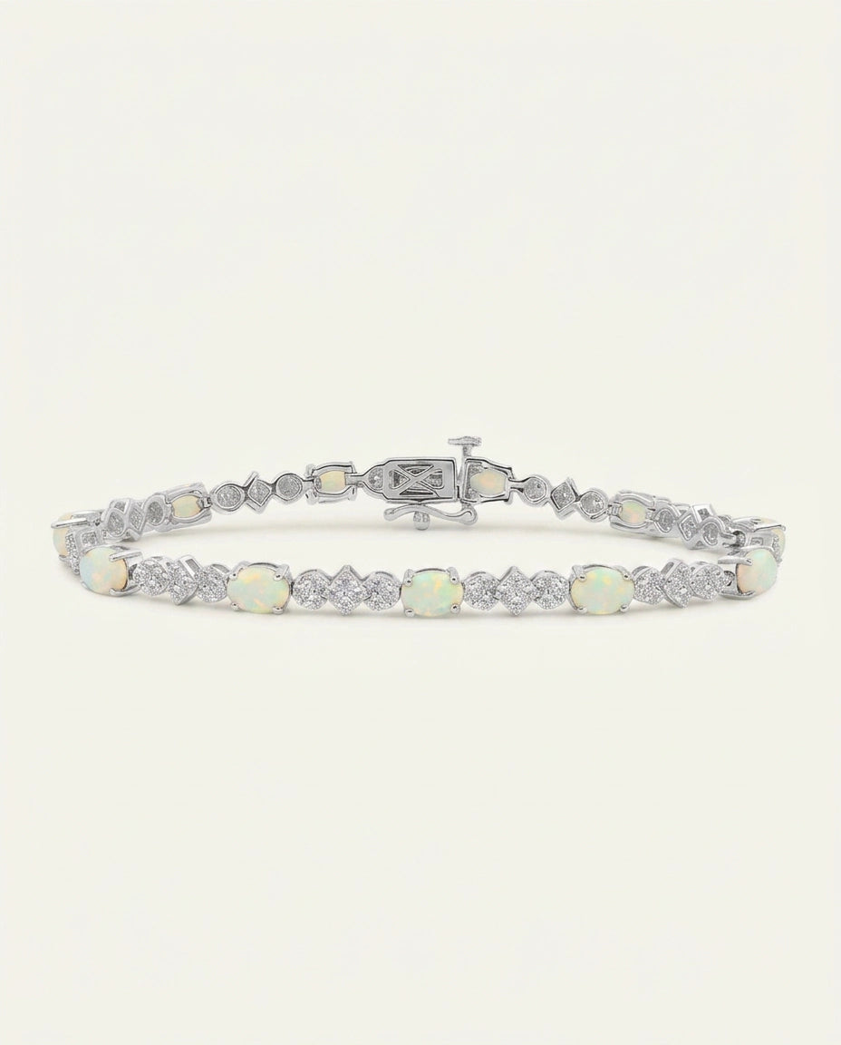 A silver tennis bracelet featuring round white opal gemstones and pavé-set clear stones, displayed on a clean off-white background.