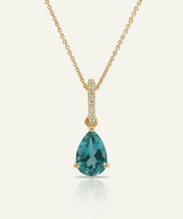 Gold necklace with a green teardrop pendant on a white background