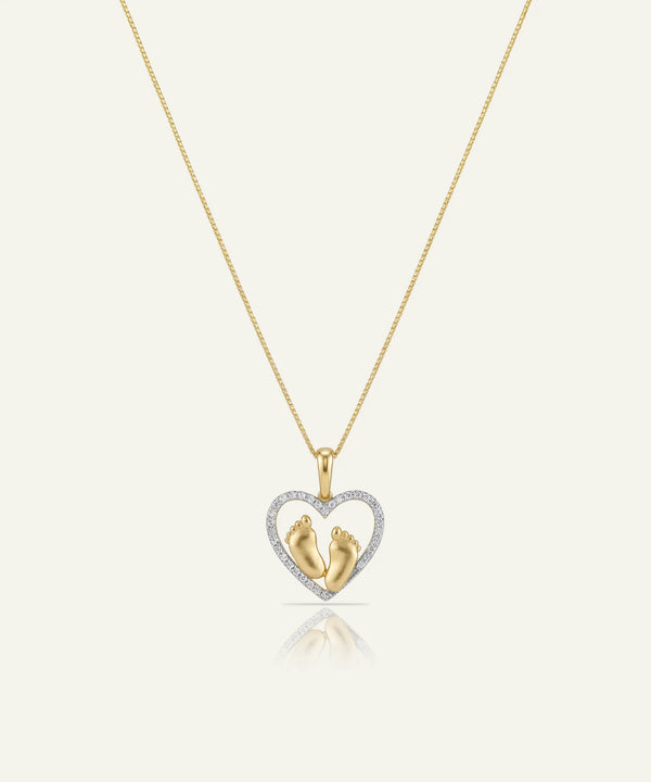 Gold necklace with a heart-shaped pendant featuring two small figures, on a white background.
