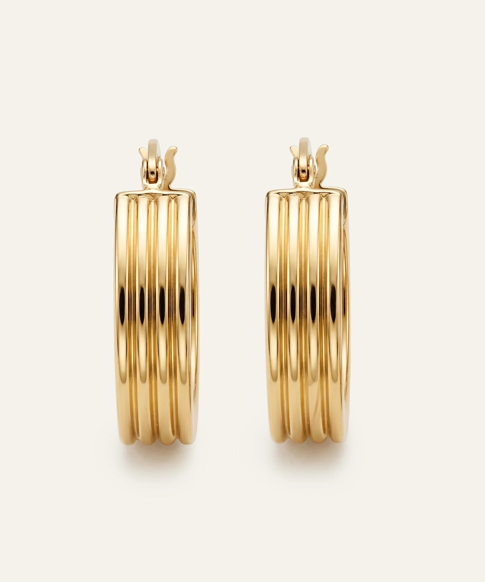 Gold hoop earrings on a light beige background