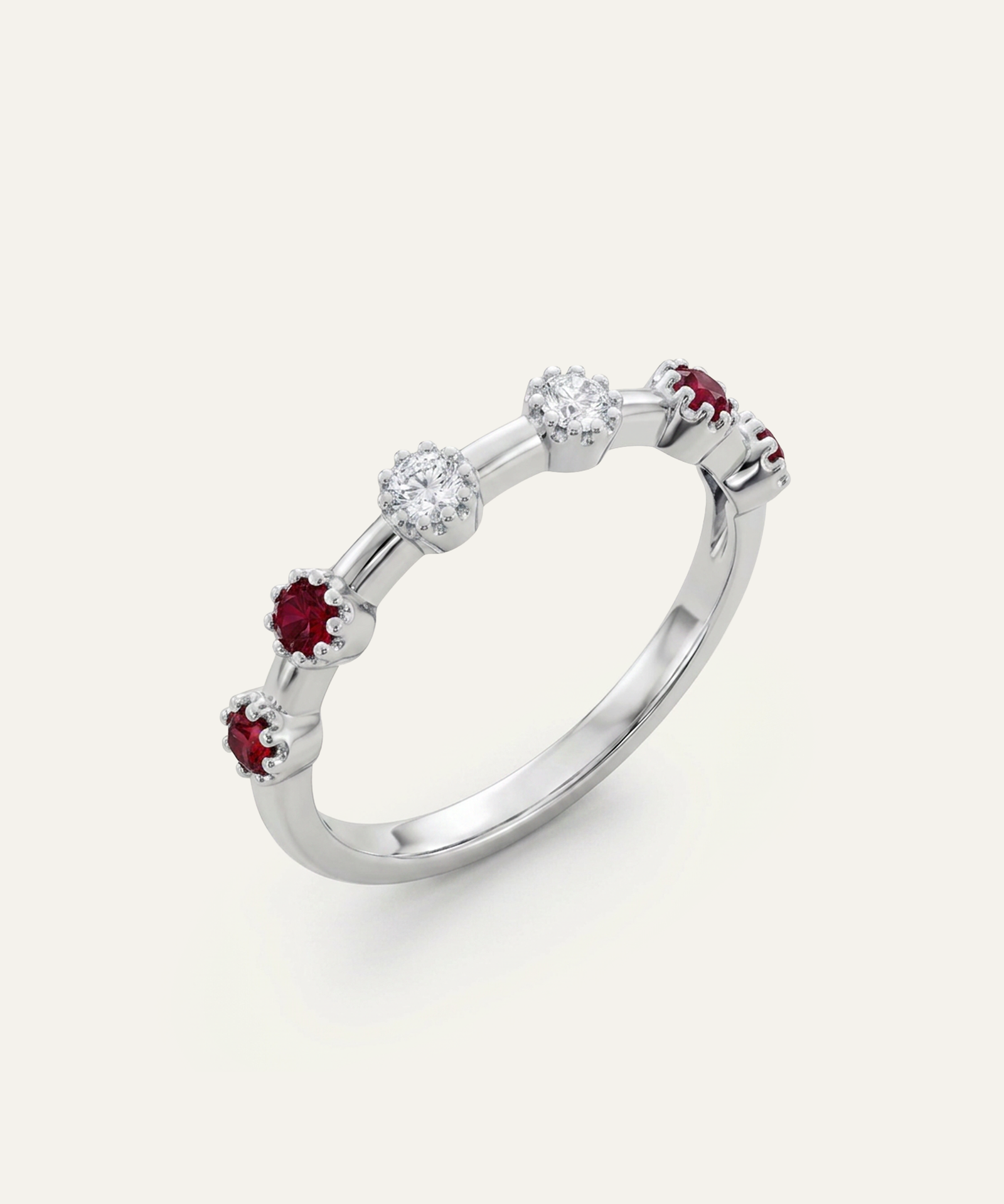A silver-toned diamond and ruby ring with alternating round-cut clear diamonds and small round-cut red rubies, shown on a light cream background.