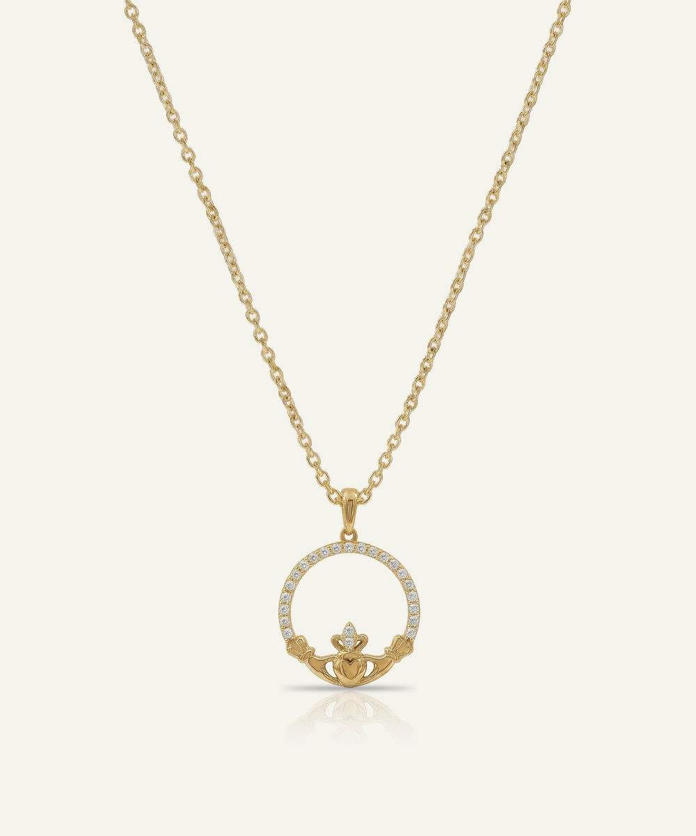 Gold necklace with a claddagh pendant on a white background