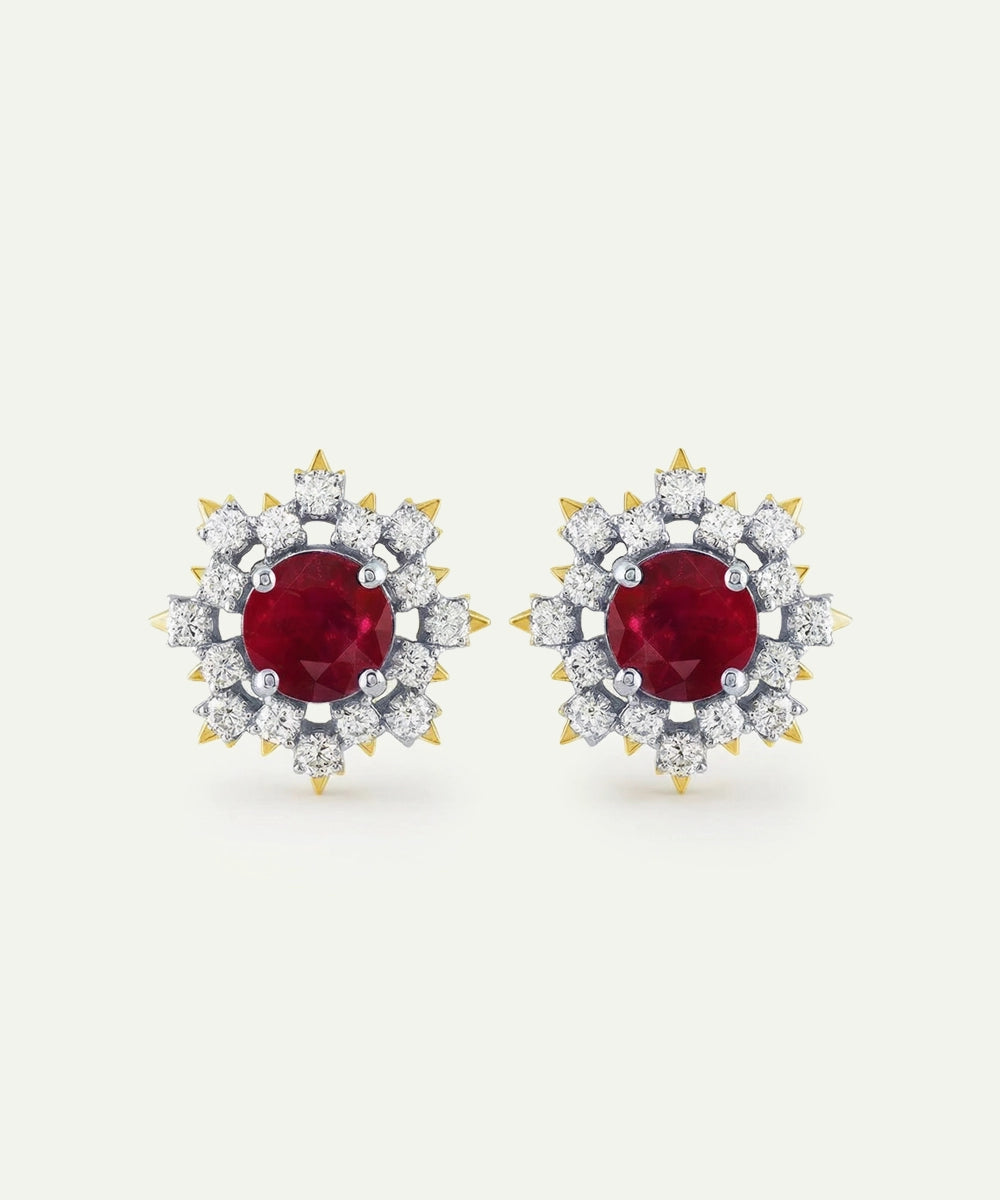 Pair of earrings with red gemstones and diamond-studded halo on a white background