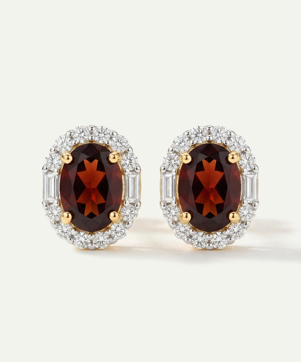 Pair of earrings with red gemstones and gold accents on a white background