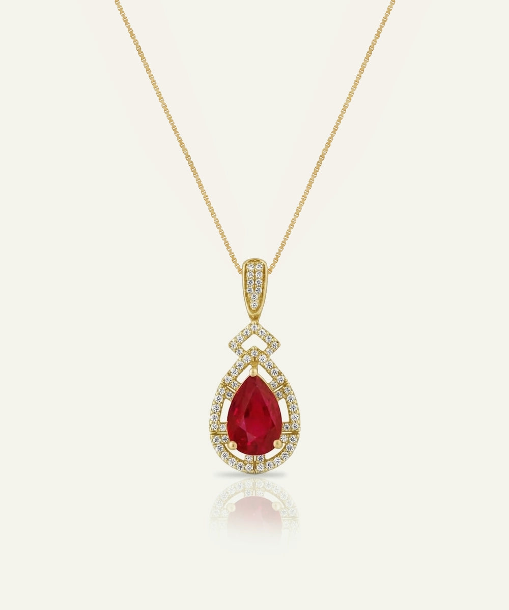 Gold pendant with a red gemstone on a white background