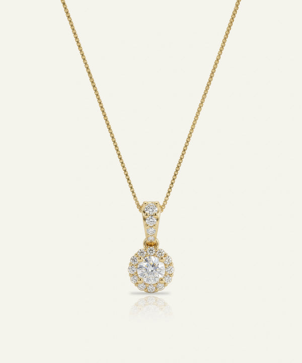 Gold necklace with a diamond pendant on a light beige background