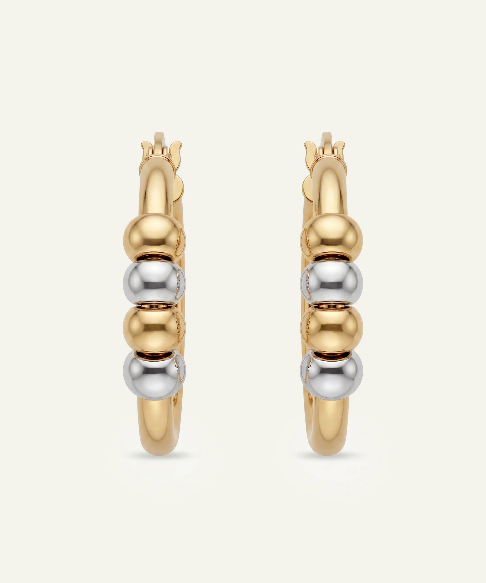 Gold and silver hoop earrings on a light beige background
