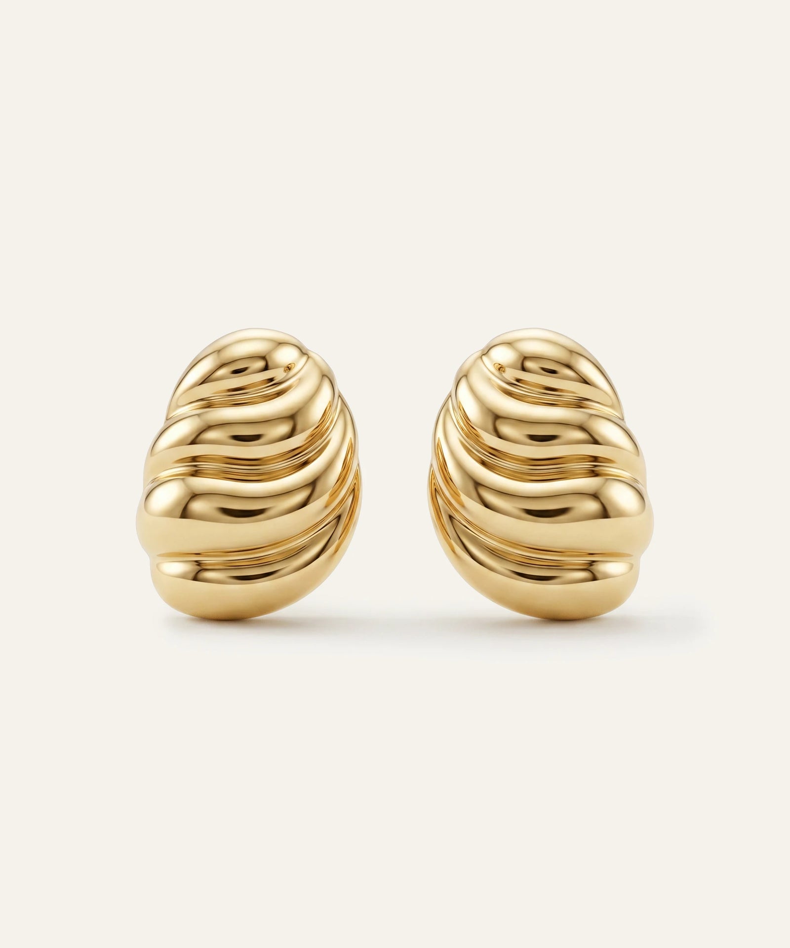 Pair of gold earrings on a light beige background
