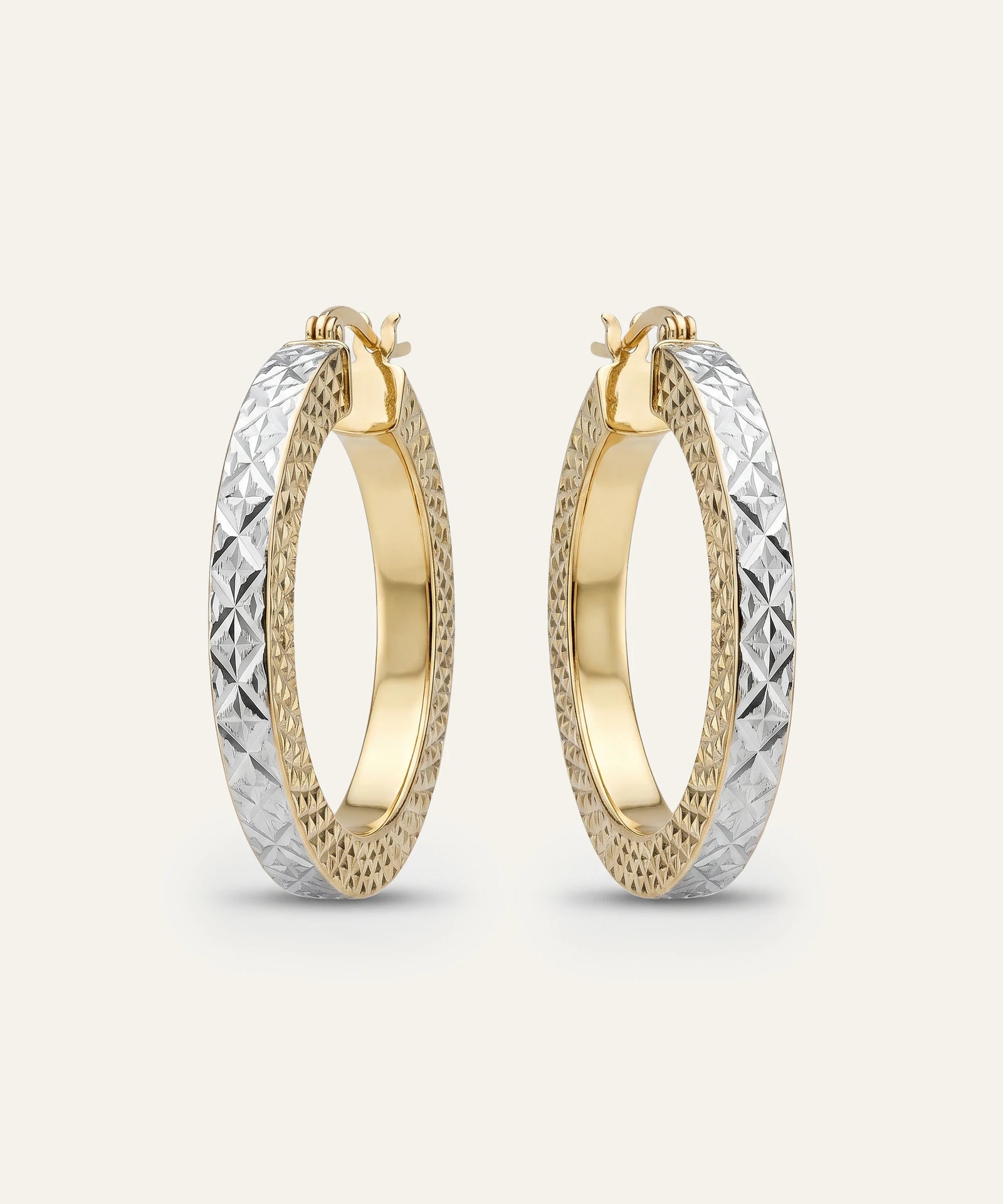 Gold and silver hoop earrings on a light beige background