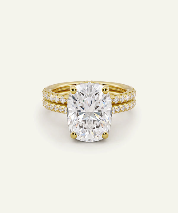 A yellow gold engagement ring featuring a large oval-cut diamond center stone, accented by a matching double-row diamond-paved band, set against a clean off-white background.