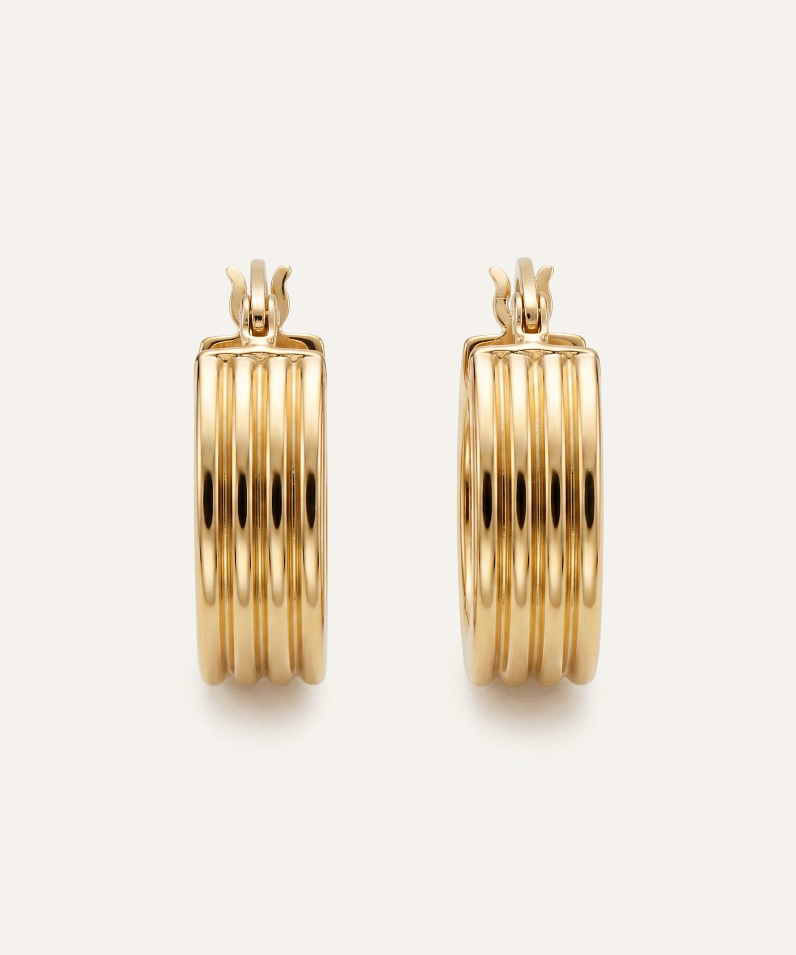 Gold hoop earrings on a light beige background