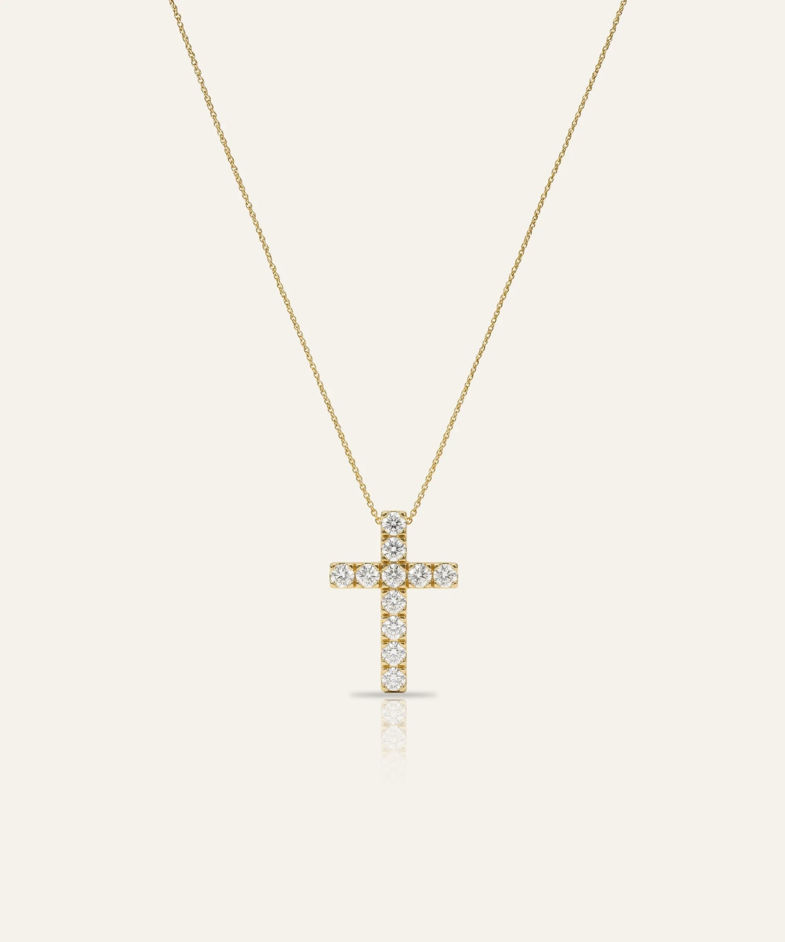Gold cross necklace with diamonds on a light beige background