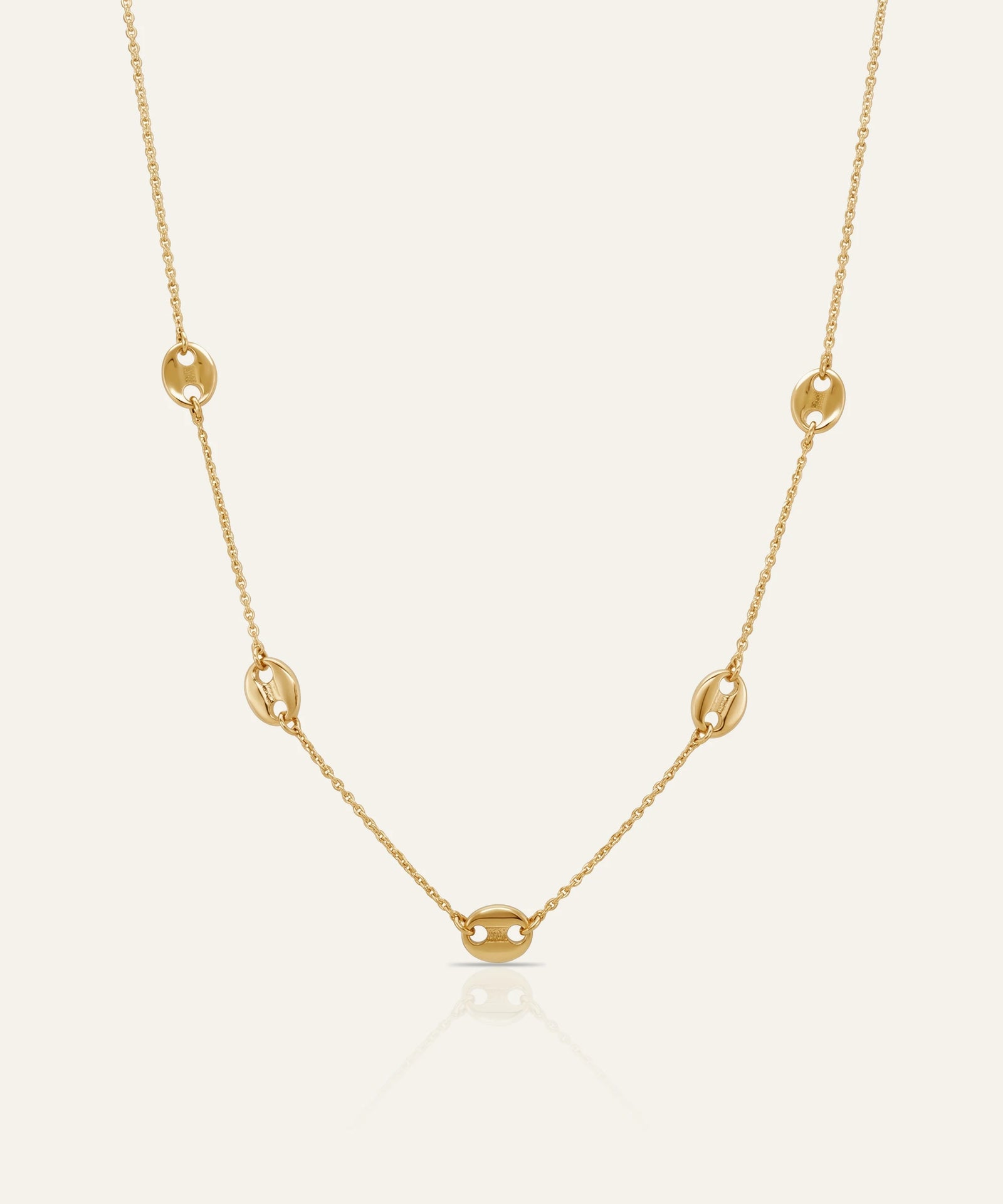 Gold necklace on a light beige background