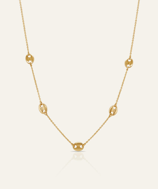 Gold necklace on a light beige background