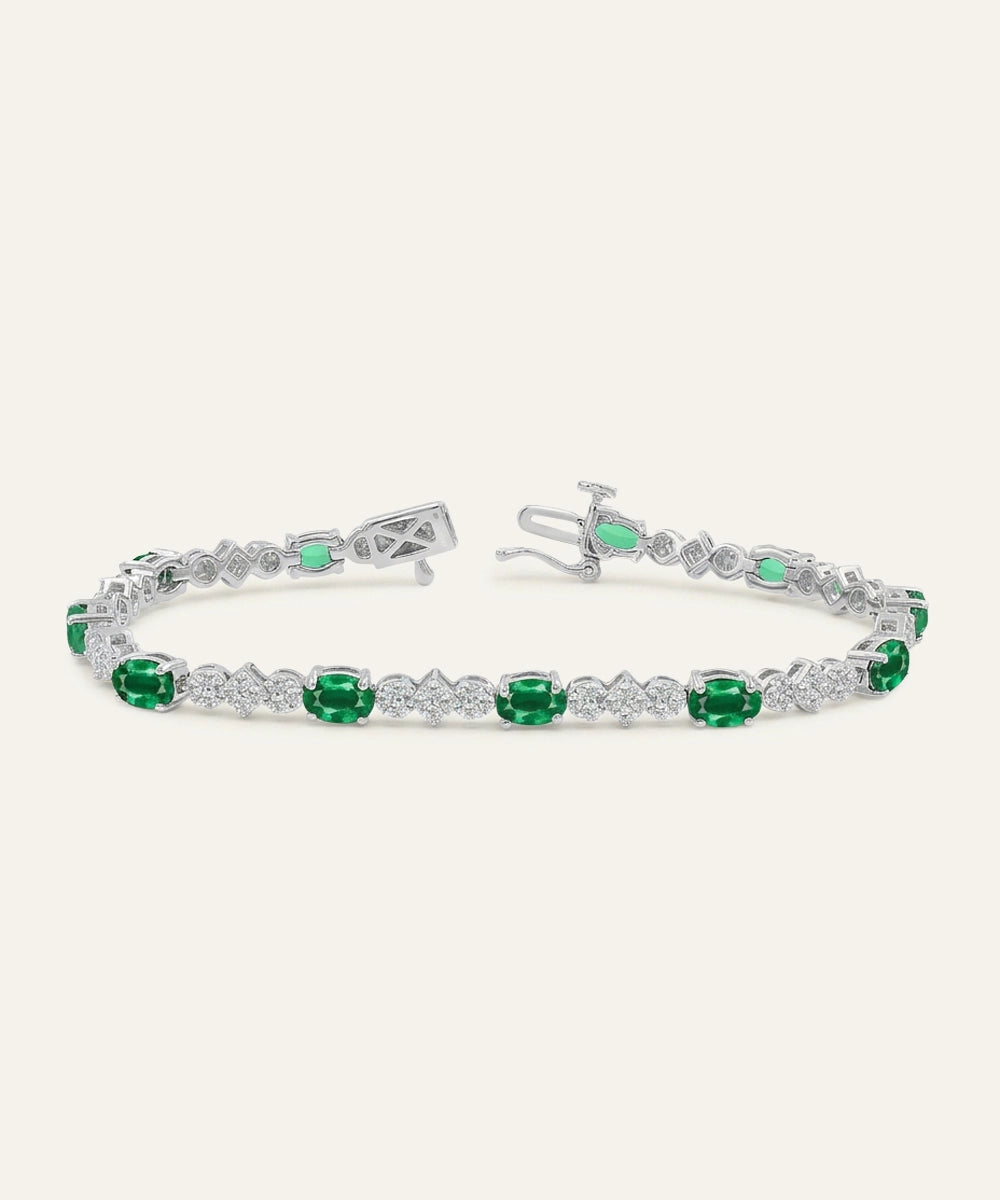 Silver bracelet with green gemstones on a white background