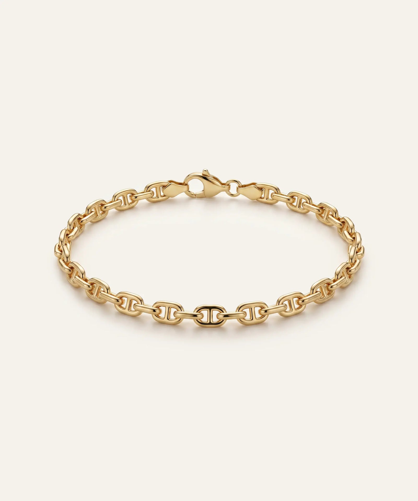 Gold chain bracelet on a light beige background